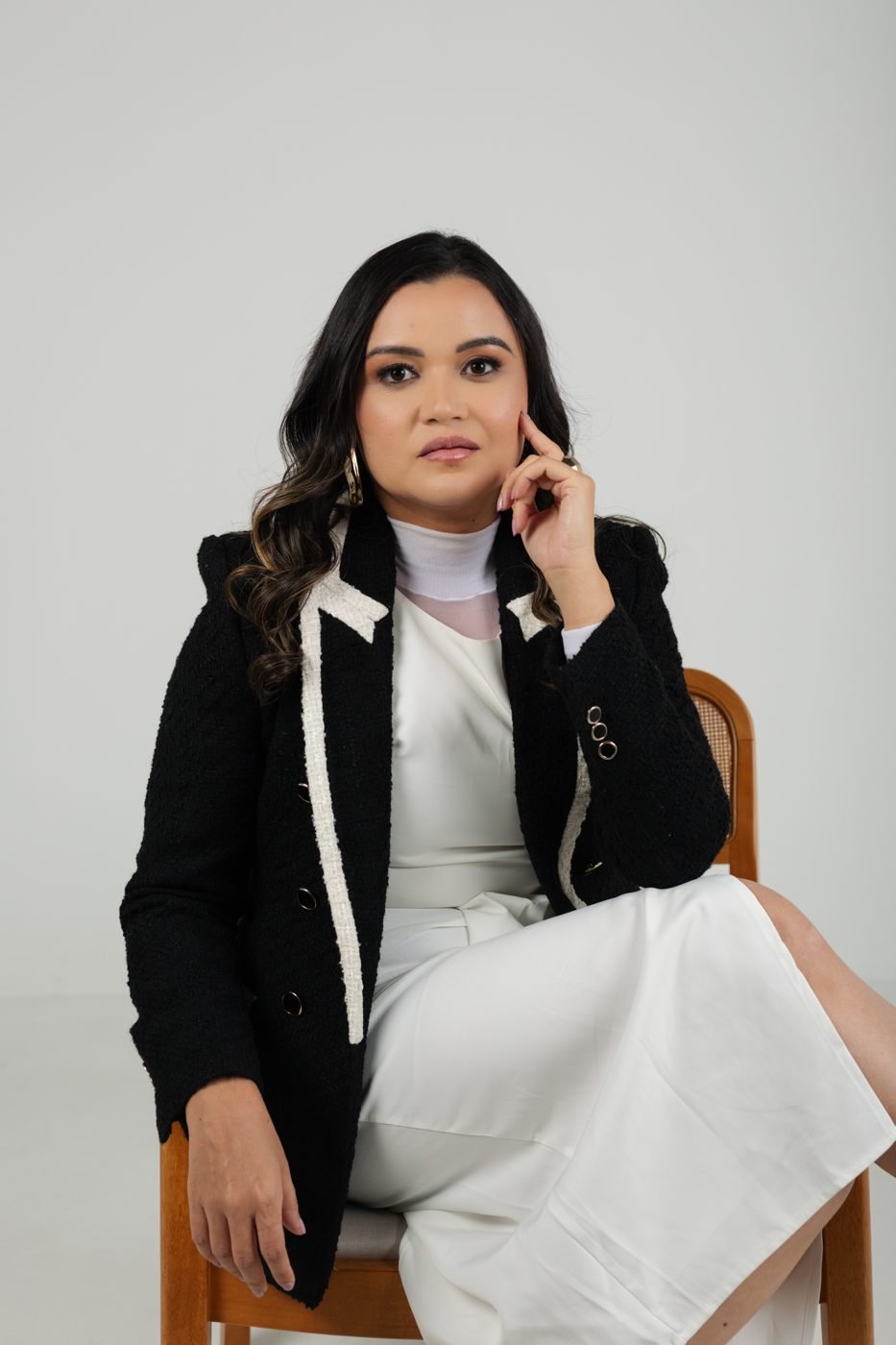 Retrato de Rayanielen Rodrigues sentada, de blazer preto